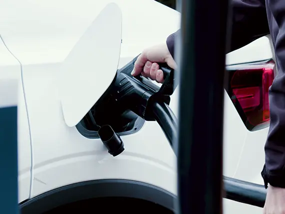 Quelqu'un remplissant sa batterie EV tenant une fiche.