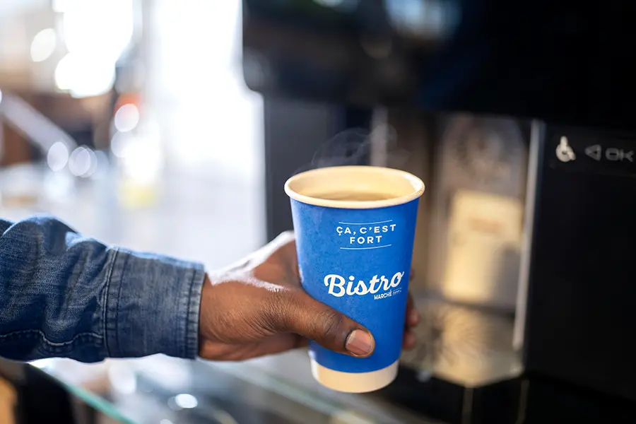 Main tenant une tasse de café Bistro remplie de café.