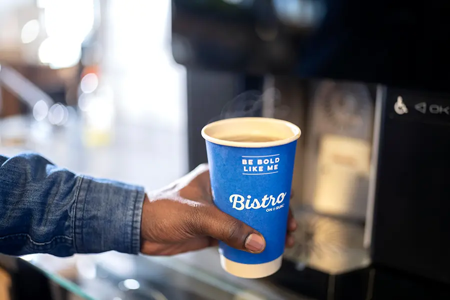 Hand holding a Bistro coffee cup filling up with coffee.